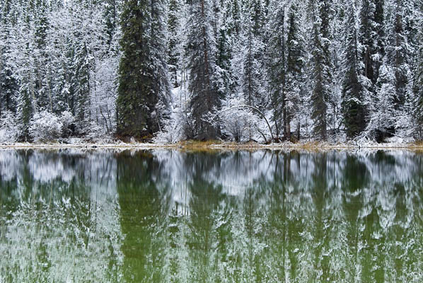 Snowy landscape reflected in green
                lake